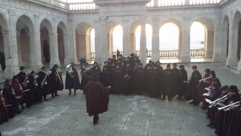 Gruppo di persone in abiti tradizionali che canta in un cortile.