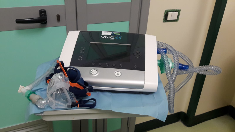 Ventilatore medico con tubi e maschera su un tavolo.
