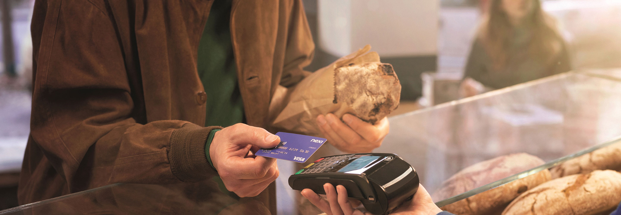 Persona che paga con carta di credito presso un negozio di alimentari.