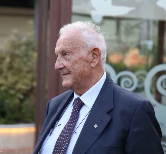 Uomo anziano con giacca e cravatta, in posa.