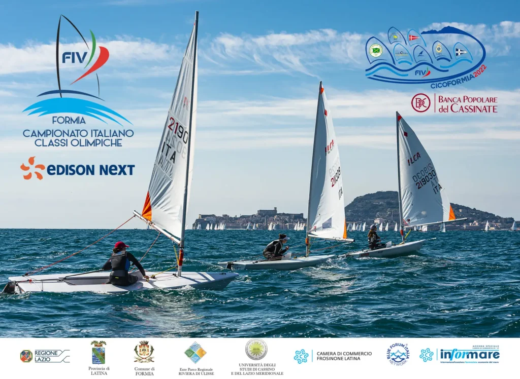 Regata di vela con barche a vela in competizione sul mare, con il logo del Campionato Italiano classi Olimpiche 2022.